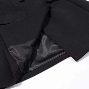 Detail of a black double-breasted blazer dress showing the pocket flap and silk lining