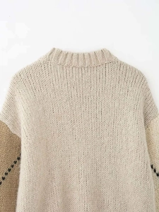 Détail du pull en maille épaisse abricot avec col rond côtelé et finitions contrastées