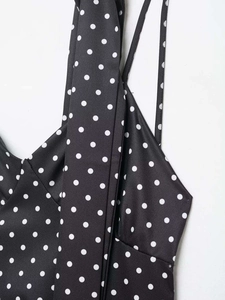 Vue détaillée de pois blancs sur tissu noir avec de fines bretelles spaghetti