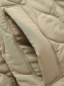 Detailed close-up of wavy quilted khaki jacket showing stitching and side pocket texture