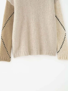 Détail d'un pull en maille color-block avec panneaux beiges et motifs de losanges