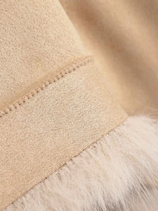 Detailed macro view of beige knit fabric with plush white faux fur trim on coat edges