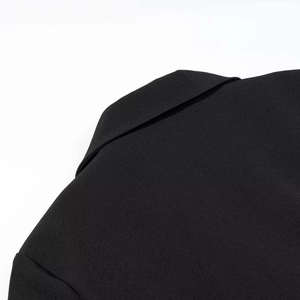 Close-up detail of structured shoulder and notched lapel on black double-breasted dress