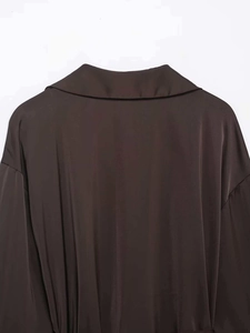 Détail d'un col de chemise en satin café noir avec texture lisse et coutures de qualité