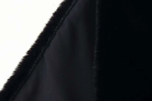 Close-up of black faux fur texture and smooth inner lining on a high-collar vest