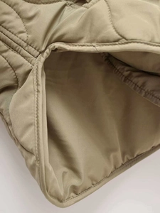 Detailed macro view of khaki wave-quilted jacket featuring precision edge stitching and lining
