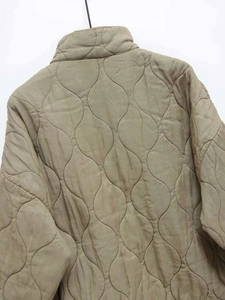 Close-up of khaki quilted jacket featuring unique leaf pattern stitching and high neck