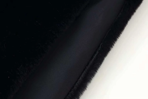 Close-up of black faux fur texture and smooth inner lining of a sleeveless vest