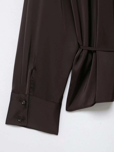 Détail de la manchette de chemise en satin marron avec deux boutons et lien de serrage