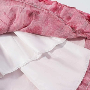Detail view of pink floral chiffon fabric with delicate ruffle hem and white inner lining