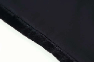 Detail of black vest showing seamless stitching between woven fabric and plush faux fur