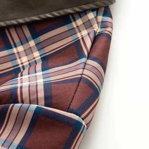 Detail of vintage brown faux leather jacket with blue and beige plaid fabric lining