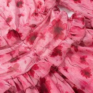 Detail of pink floral chiffon dress featuring intricate ruffled edges and vibrant print