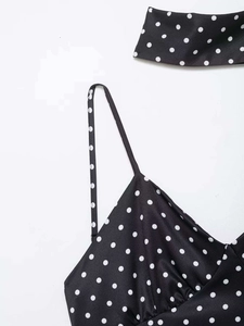 Gros plan d'une robe en satin noir à pois avec de fines bretelles et un tour de cou
