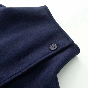 Détail de la veste en laine bleu marine montrant le tissu texturé et le bouton noir