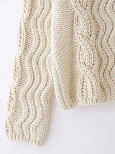 Detailed macro view of cream cable knit texture and intricate weave on high collar sweater