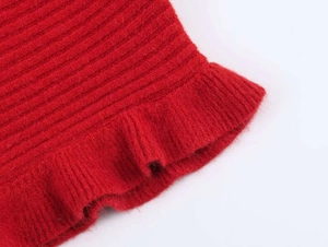 Detail of red knitted fabric with vertical ribbed texture and ruffled edge design