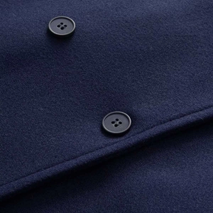 Gros plan sur la veste en laine bleu marine montrant des boutons noirs mats et le tissu