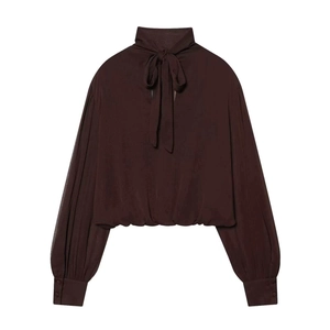 Detail of elegant dark brown blouse with bow-tie high neck and lantern sleeves texture