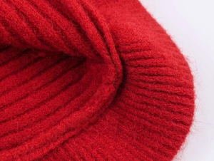 Detailed close-up of the bright red ribbed knit fabric texture and soft wool fibers