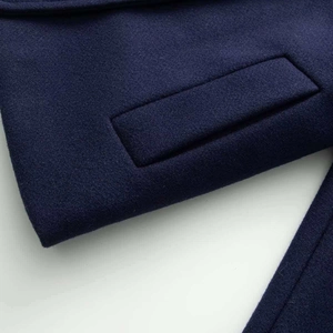 Gros plan sur la poche du manteau en laine marine montrant les coutures et la texture du tissu