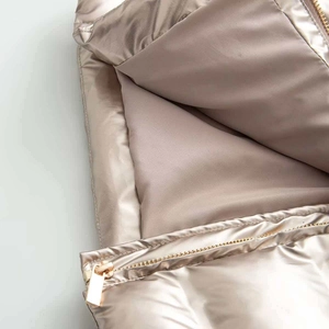 Macro shot of metallic champagne gold quilted jacket with premium golden metal zipper detail