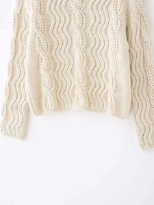 Detail of chunky cable knit texture on cream oversized high neck sweater