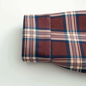 Close-up of shirt cuff featuring multi-color plaid pattern and detailed stitching