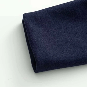 Détail du tissu en laine bleu marine montrant la texture fine et les finitions de l'ourlet