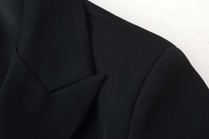 Detail view of the notch lapel and shoulder stitching on a black tailored blazer