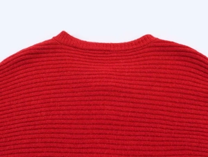 Detailed close-up of red knit sweater featuring a round neck and ribbed texture detail