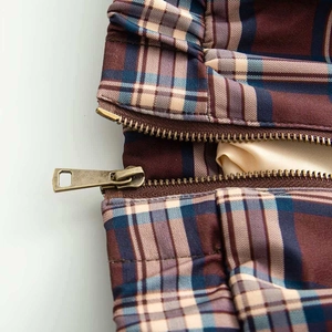 Detail of vintage plaid jacket featuring bronze metal zipper and smooth beige inner lining