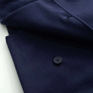 Gros plan détaillé sur le tissu en laine bleu marine et bouton noir d'un manteau court