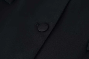 Detailed macro view of high-density black fabric with fabric-covered button and stitch