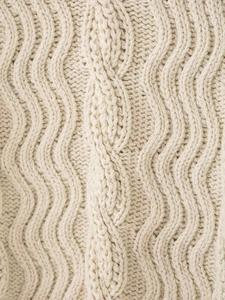 Detailed close-up of premium cream cable knit patterns on a thick autumn sweater