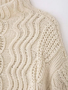 Close-up of premium cream cable-knit texture and ribbed high-collar neckline detail
