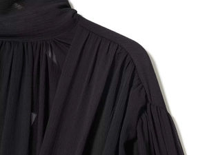 Close-up of pleated collar and puff sleeve details on black chiffon elegant blouse