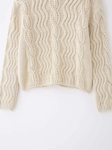 Close-up of cream chunky cable knit sweater showing textured hem and cuffs detailing