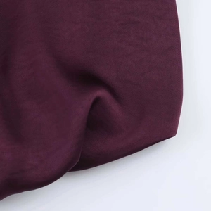 Detail of luxury burgundy satin fabric showing smooth texture and elegant drape for shirts