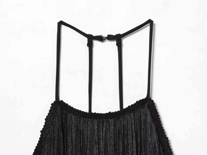 Detail view of black pleated dress featuring thin shoulder straps and small metal buckle