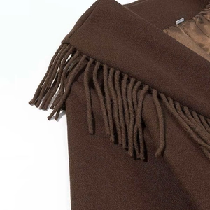 Detailed close-up of brown wool coat shoulder featuring decorative tassel fringe and premium fabric