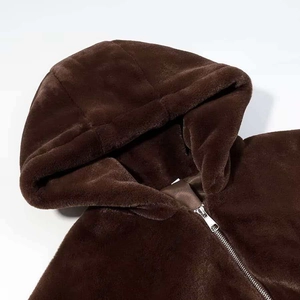Detailed close-up of dark brown plush faux fur fabric and silver zipper on hooded jacket