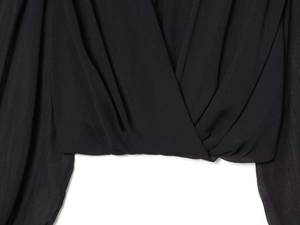 Detail showing the elegant V-neck wrap design and textured black chiffon fabric on top