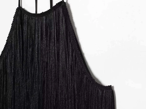 Detailed view of the black halter dress featuring elegant vertical fringe textures