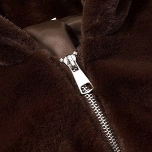 Detail of silver metal zipper on dark brown faux fur jacket with soft plush texture