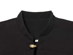 Detail of black stand-collar blazer featuring a gold olive-shaped button and fabric texture