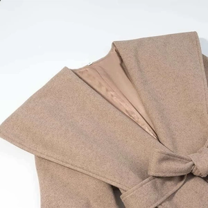 Detail of khaki wool coat showing wide shawl collar with a matching waist tie belt