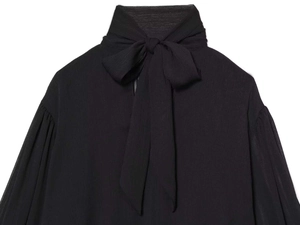 Detail of elegant black sheer chiffon top with a large bow-tie neck and textured fabric