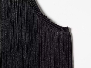 Close-up of black pleated fabric detail and smooth edge stitching on neck dress