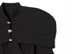 Detail of black slim fit blazer featuring shoulder pleats and gold teardrop buttons